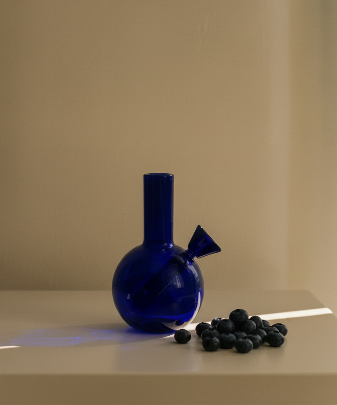 Blue glass bottle with a unique design on a beige surface