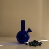 Blue glass bottle with a unique design on a beige surface